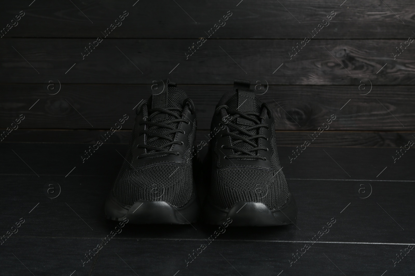 Photo of Pair of stylish black sneakers on dark wooden background