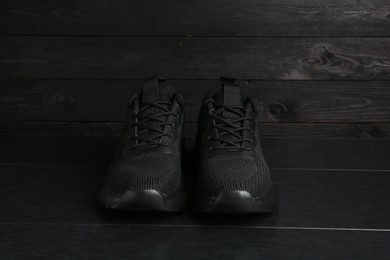 Photo of Pair of stylish black sneakers on dark wooden background