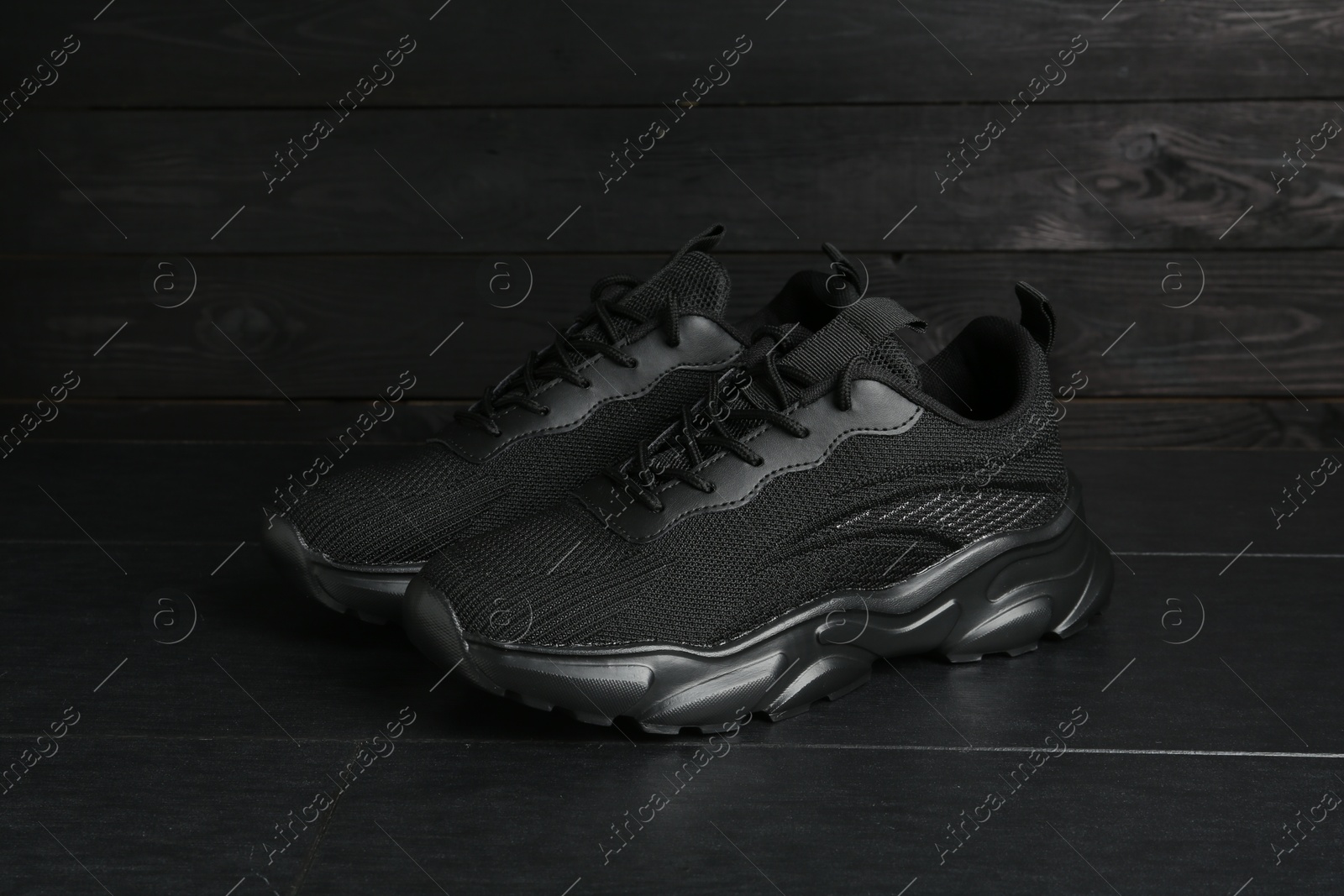 Photo of Pair of stylish black sneakers on dark wooden background