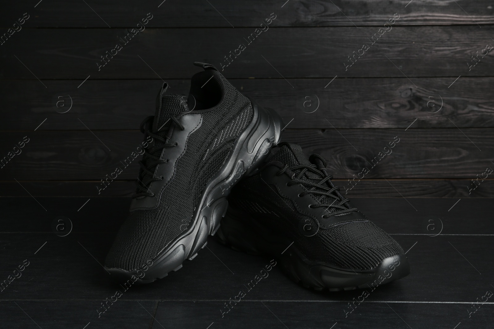 Photo of Pair of stylish black sneakers on dark wooden background