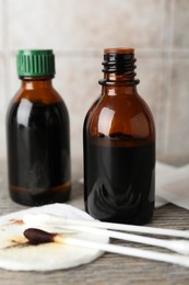 Photo of Topical iodine, cotton pad and swabs on wooden table, closeup