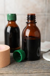 Photo of Topical iodine and adhesive bandage on wooden table, closeup