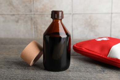 Photo of Topical iodine, adhesive bandage and first aid kit on wooden table