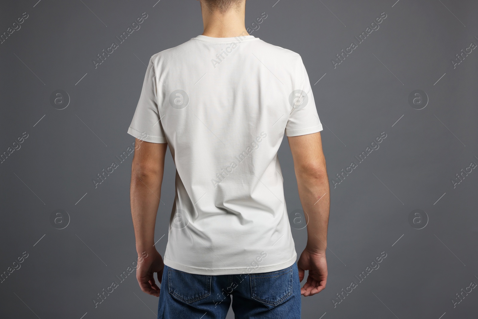 Photo of Man in stylish t-shirt on grey background, back view. Mockup for design