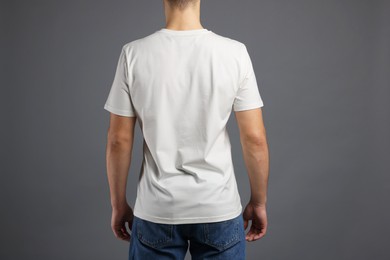 Photo of Man in stylish t-shirt on grey background, back view. Mockup for design