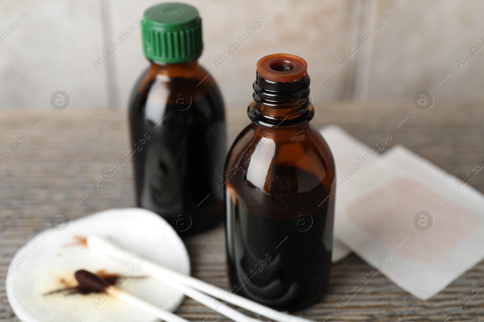 Photo of Topical iodine, cotton pad, swabs and adhesive bandages on wooden table