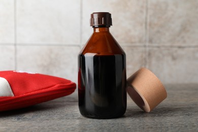 Photo of Topical iodine, adhesive bandage and first aid kit on wooden table