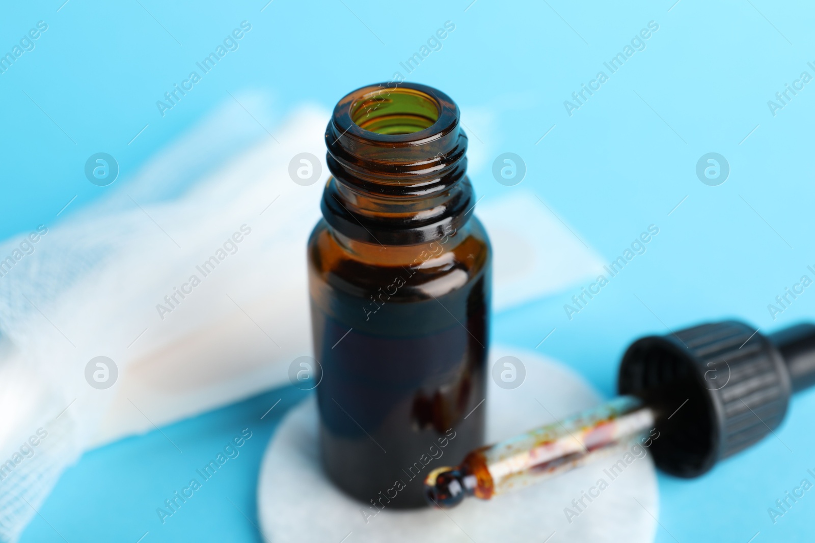 Photo of Topical iodine, cotton pad and bandage on light blue background, closeup