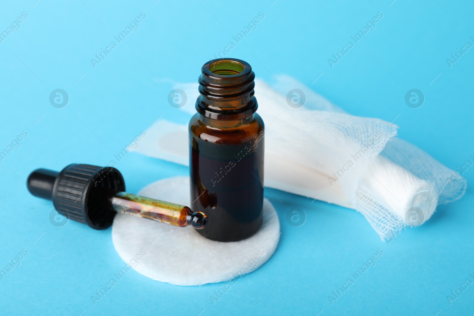 Photo of Topical iodine, cotton pad and bandage on light blue background, closeup