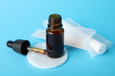 Photo of Topical iodine, cotton pad and bandage on light blue background, closeup