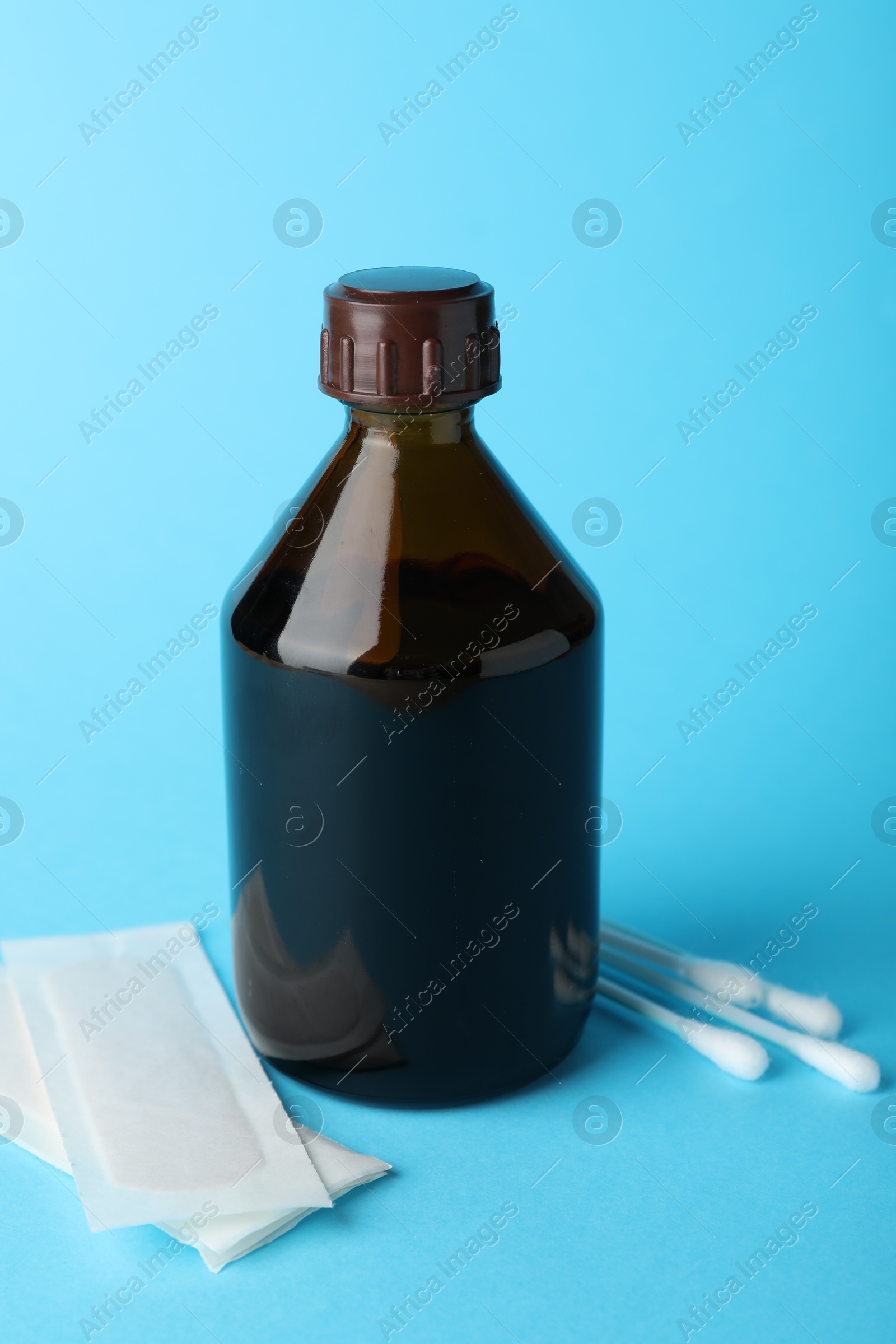 Photo of Topical iodine, cotton swabs and adhesive bandages on light blue background