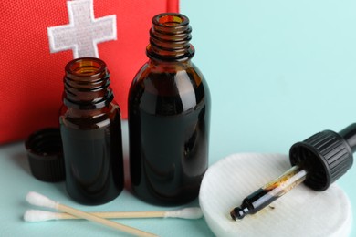 Photo of Topical iodine and other first aid kit components on light blue background, closeup