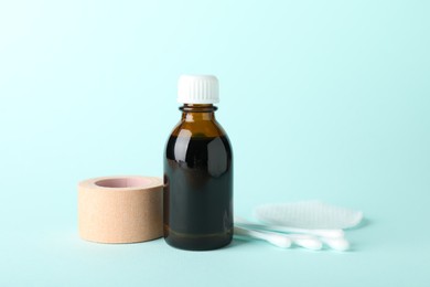 Photo of Topical iodine, cotton pad, swabs and adhesive bandage on light blue background