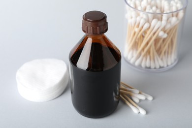 Photo of Topical iodine, cotton pads and swabs on light background, closeup