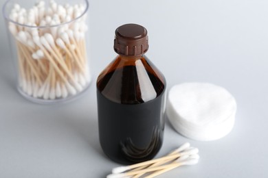 Photo of Topical iodine, cotton pads and swabs on light background, closeup