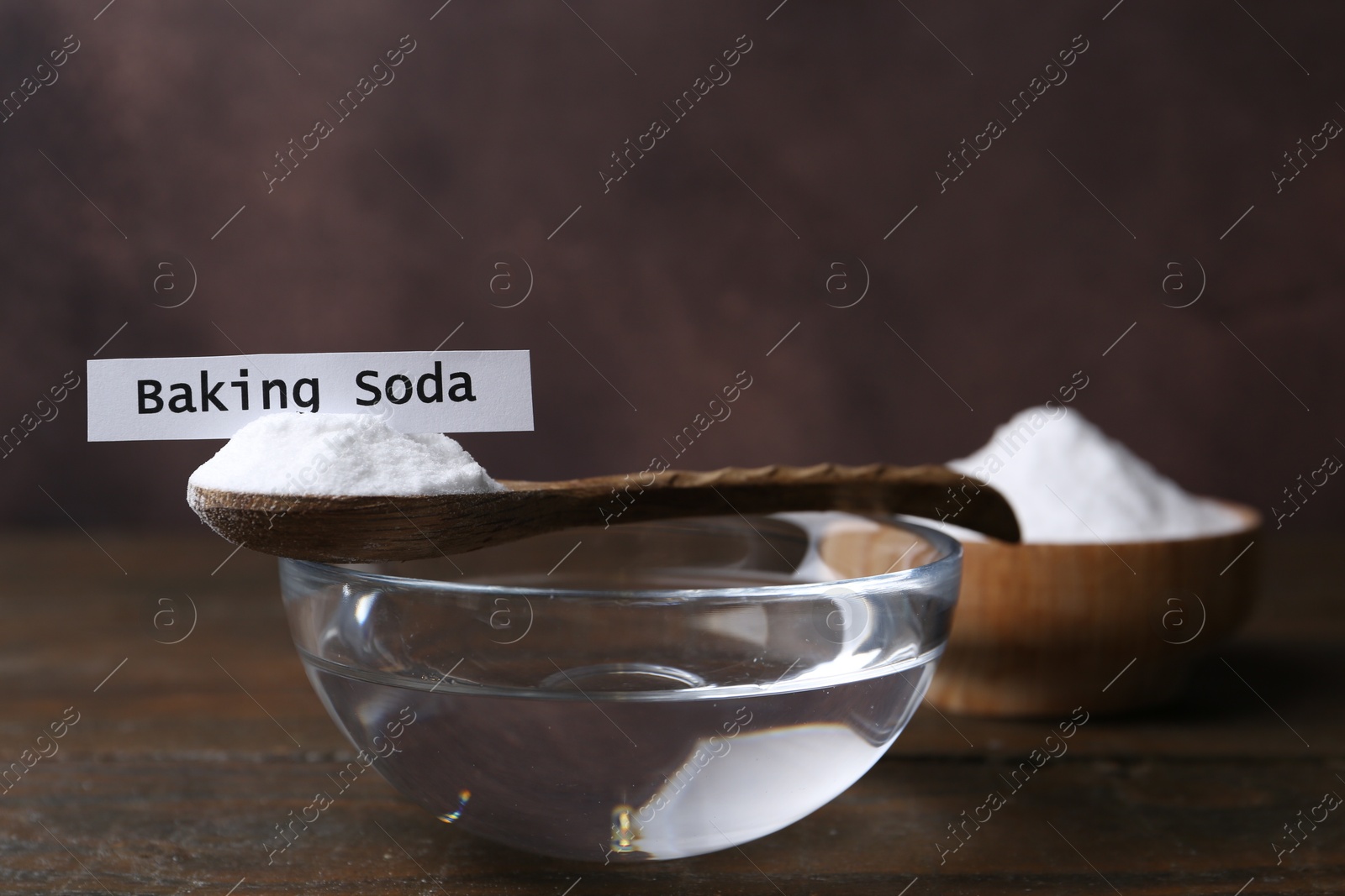 Photo of Glass of water and baking soda on wooden table