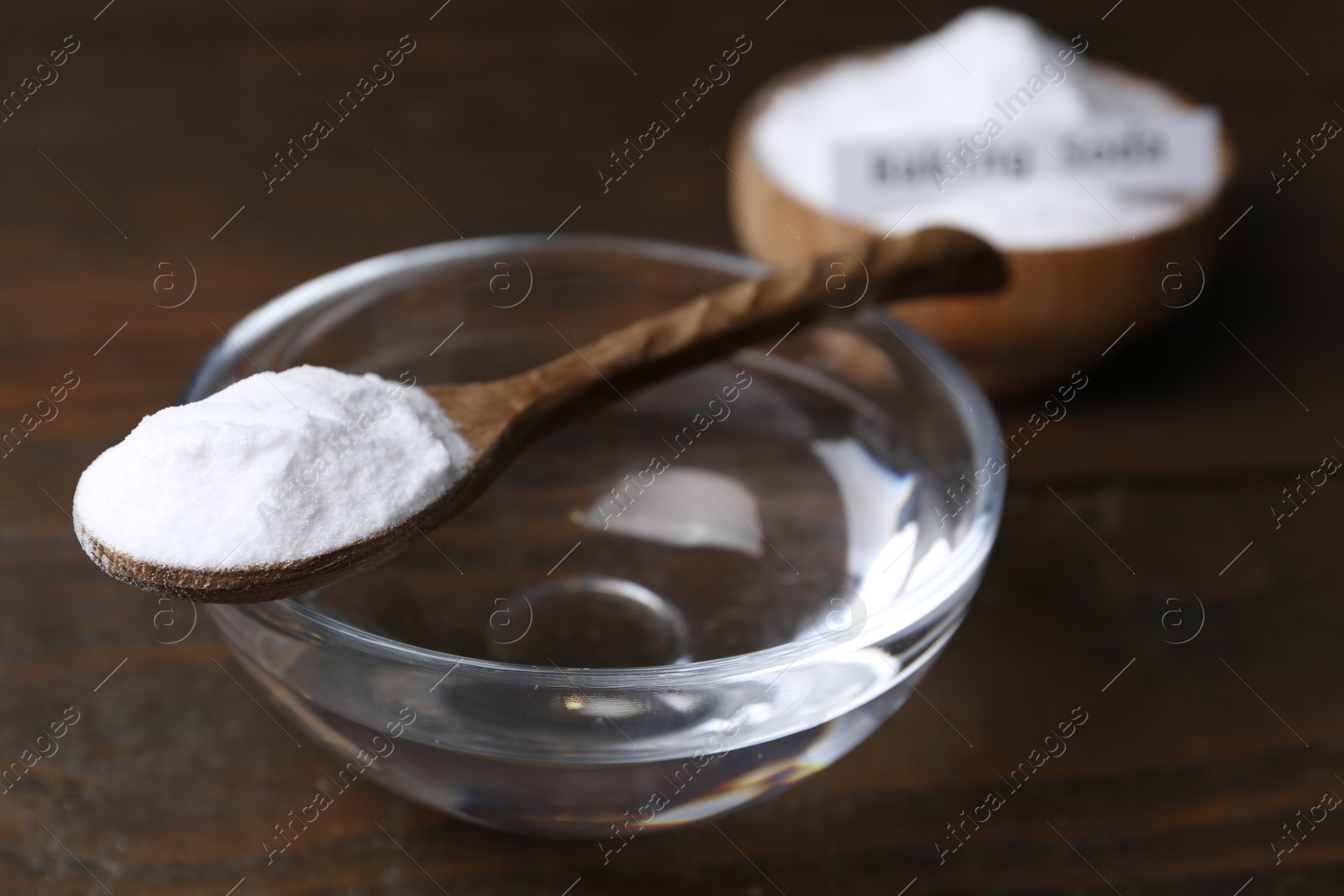 Photo of Glass of water and baking soda on wooden table, closeup