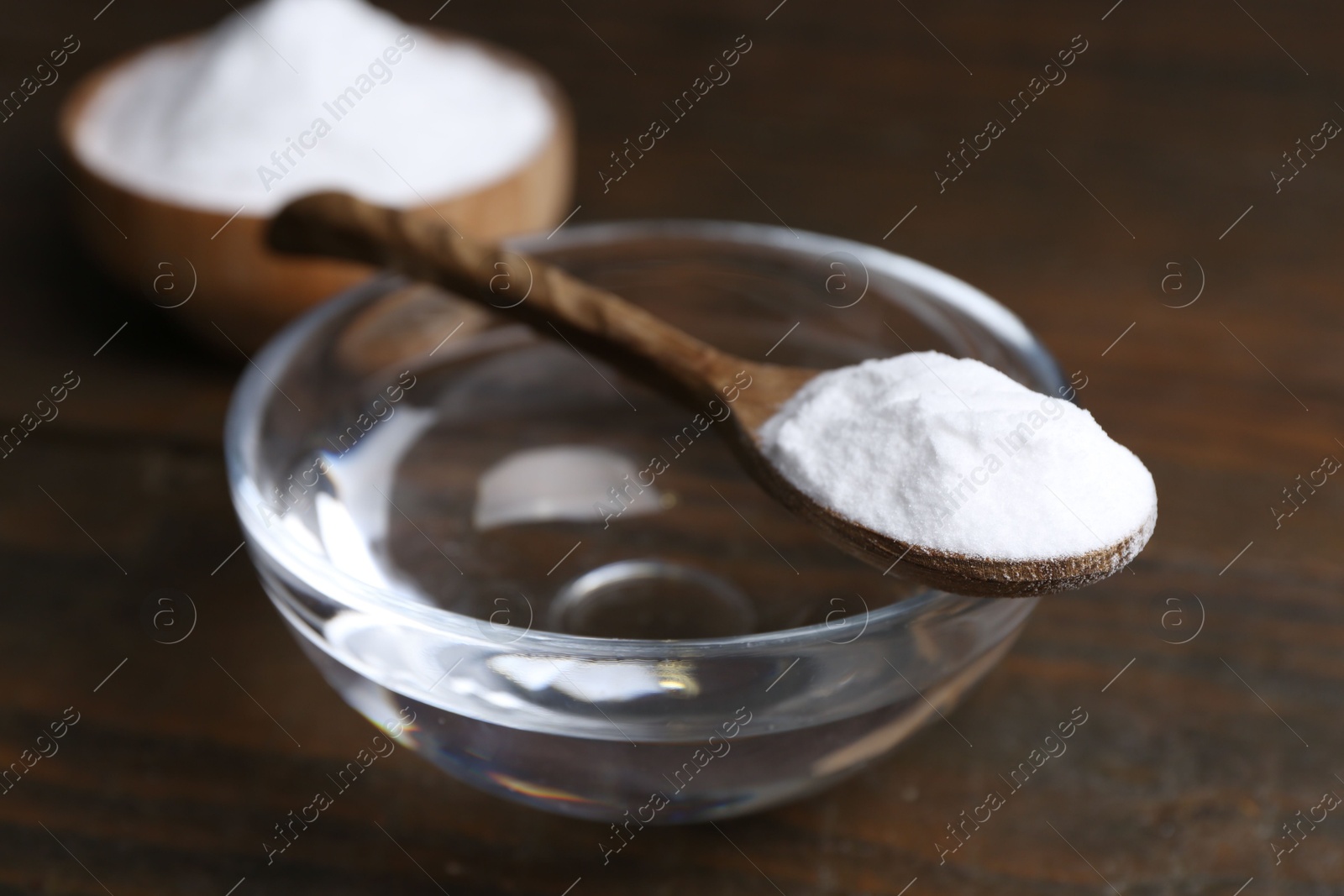 Photo of Glass of water and baking soda on wooden table, closeup