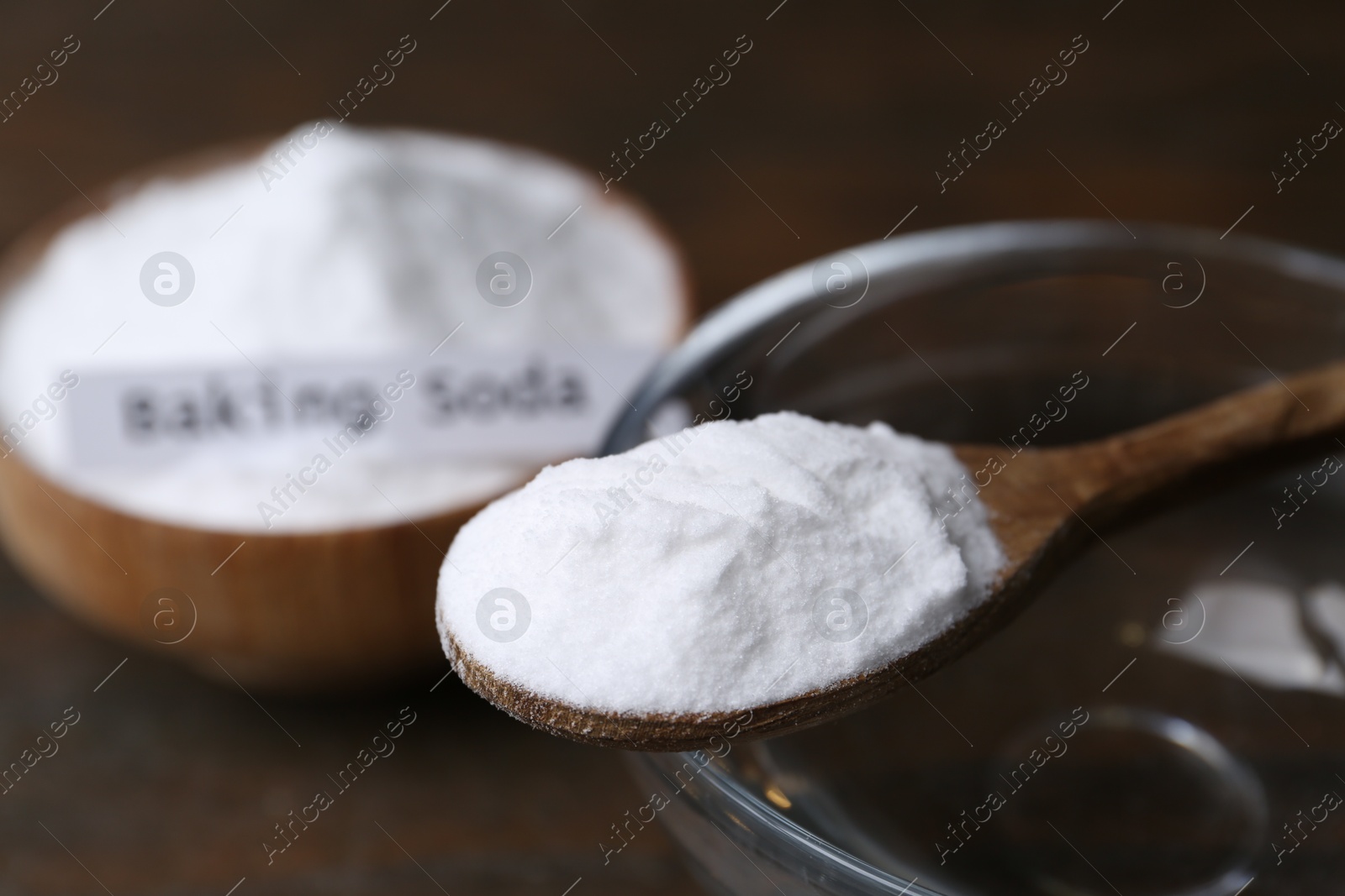 Photo of Glass of water and baking soda on wooden table, closeup