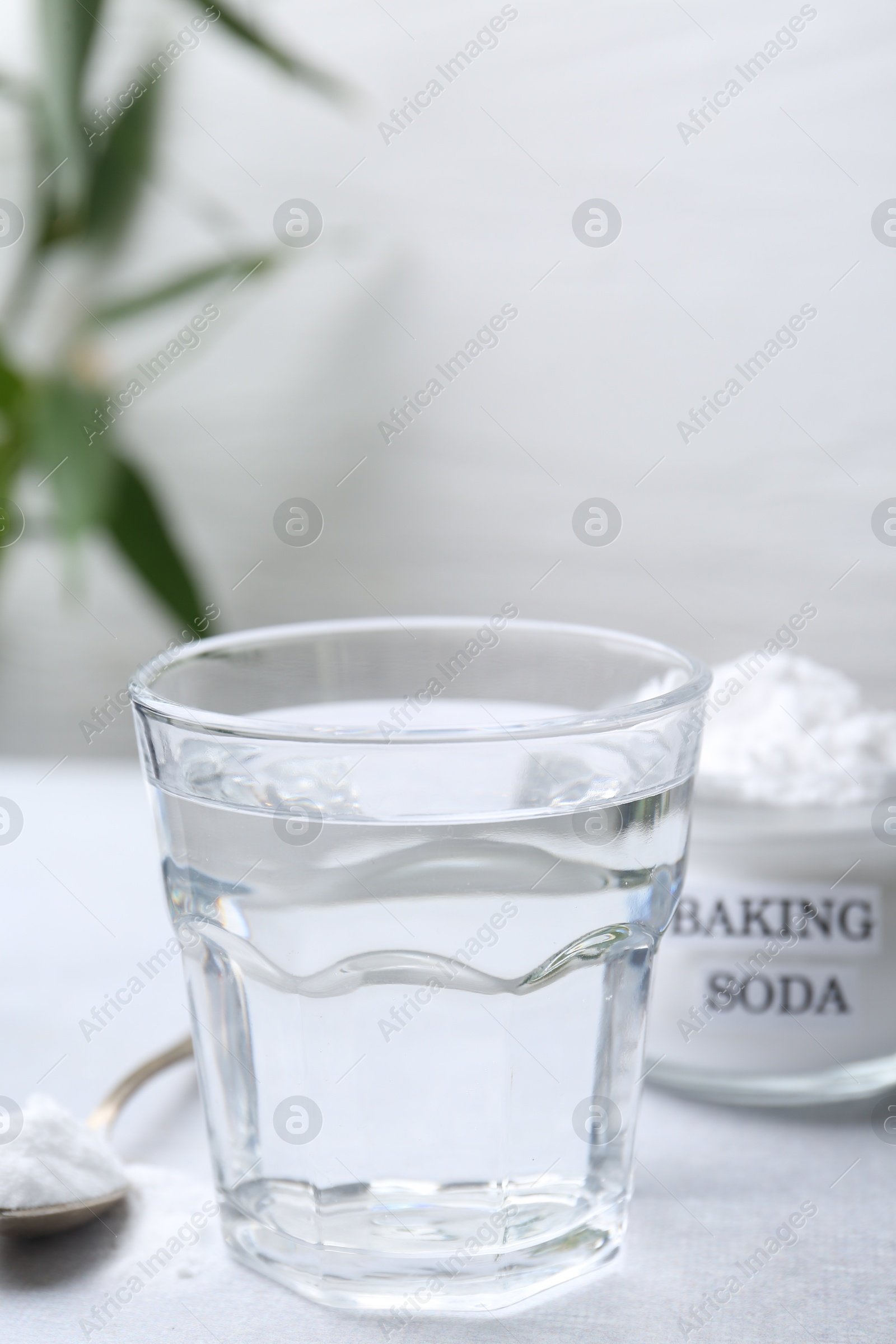 Photo of Glass of water and baking soda on white table, selective focus. Space for text