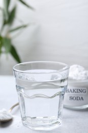 Glass of water and baking soda on white table, selective focus. Space for text