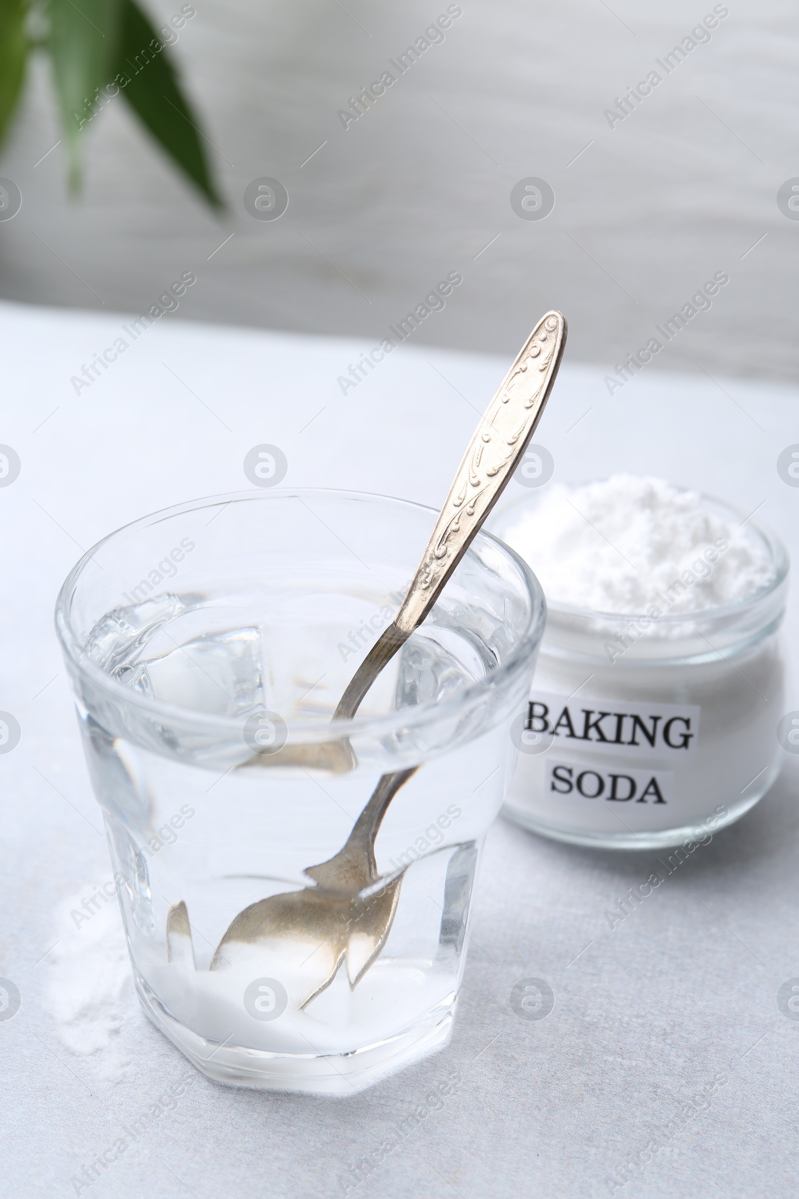 Photo of Glass of water and baking soda on white table. Space for text