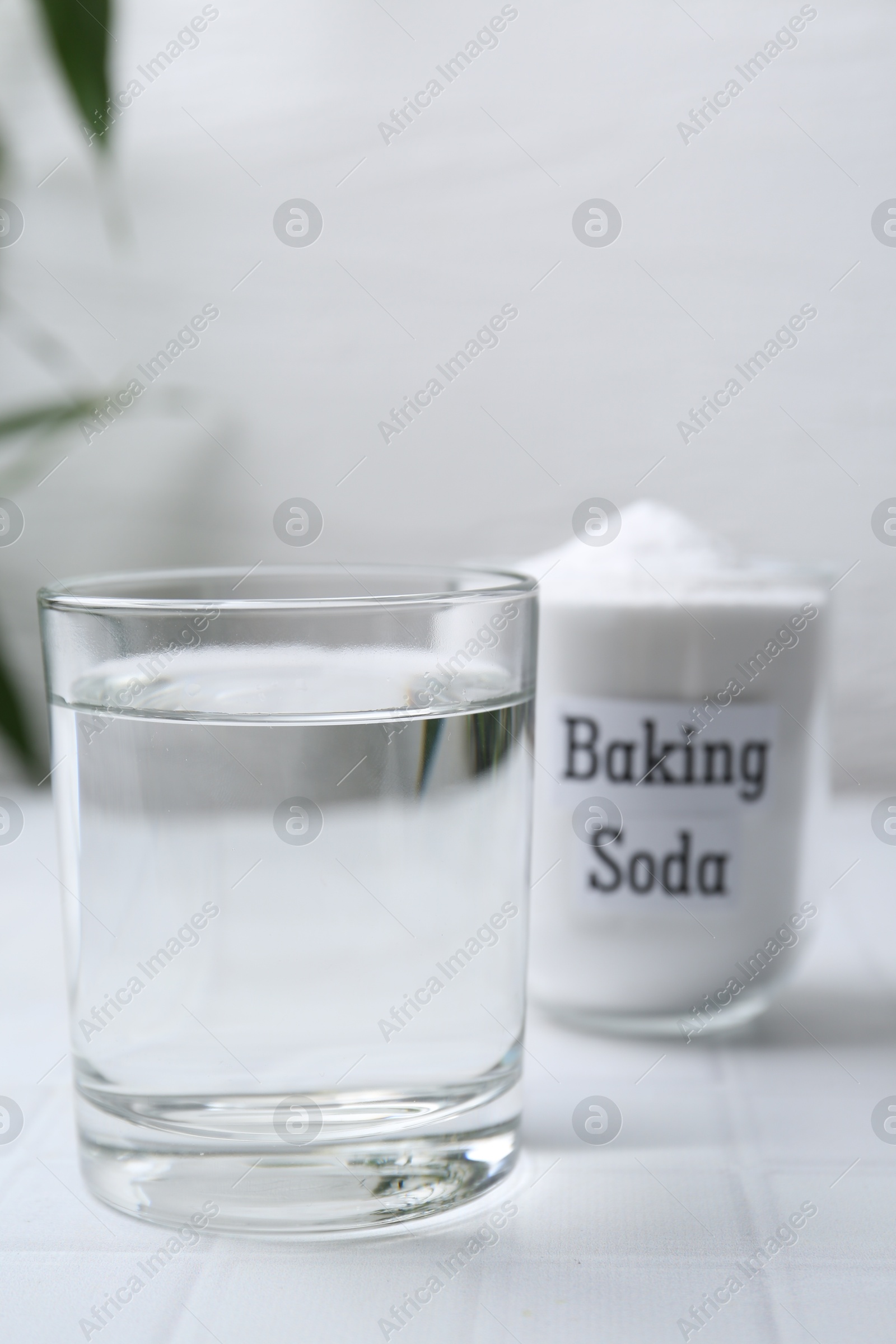 Photo of Glass of water and baking soda on white tiled table. Space for text