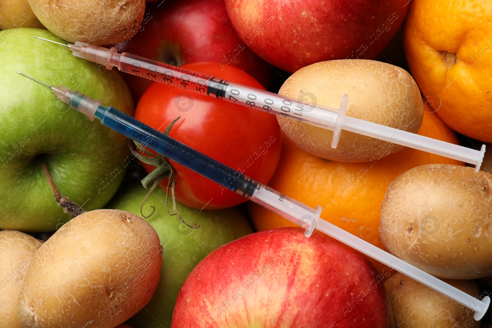 Photo of GMO concept. Different products and syringes as background, top view