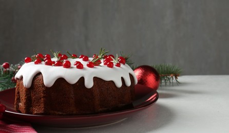 Photo of Traditional Christmas cake decorated with currants and rosemary on white table, closeup. Space for text