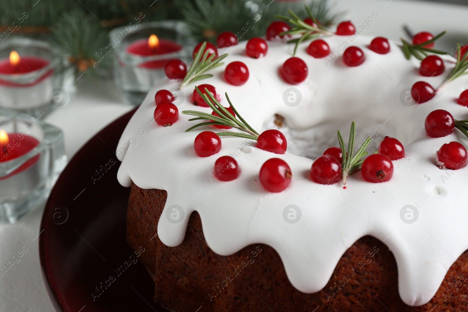 Photo of Beautifully decorated Christmas cake and burning candles on white table, closeup