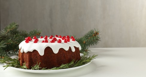 Photo of Beautifully decorated Christmas cake and fir branches on white table. Space for text