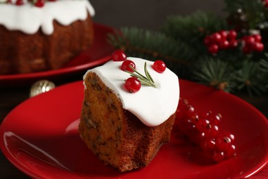 Photo of Piece of traditional Christmas cake decorated with red currants and rosemary on table, closeup