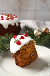 Photo of Piece of traditional Christmas cake decorated with red currants and rosemary on table