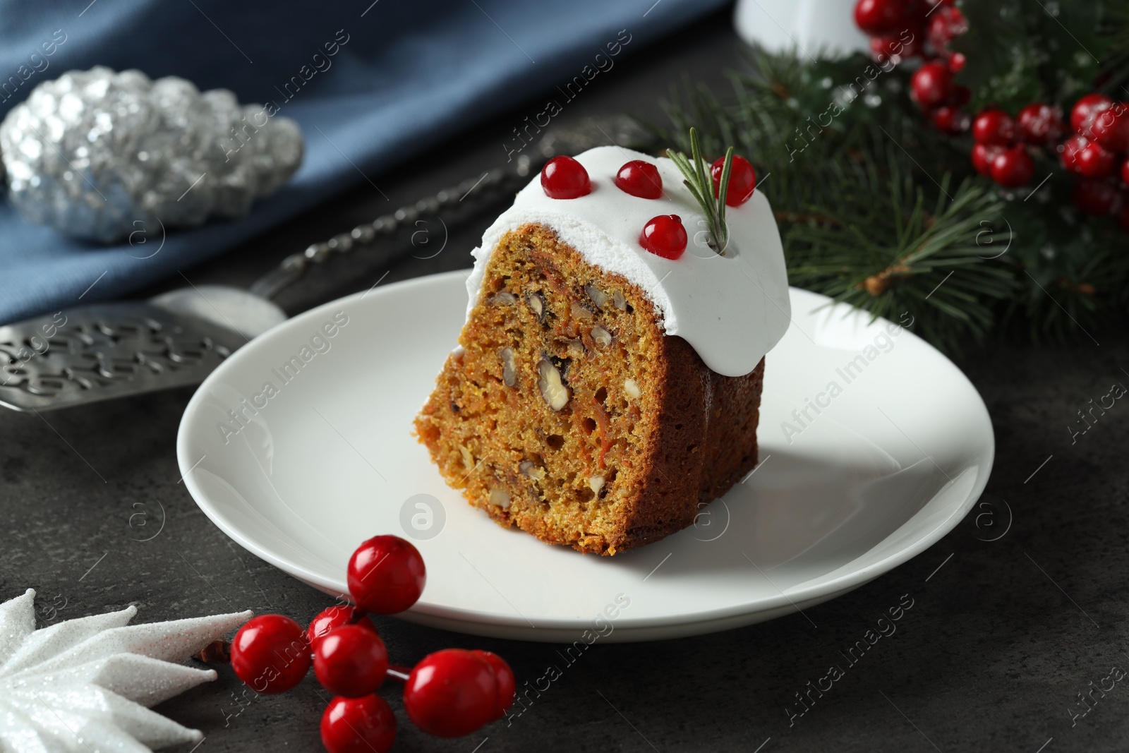 Photo of Piece of traditional classic Christmas cake and decor on gray textured table, closeup