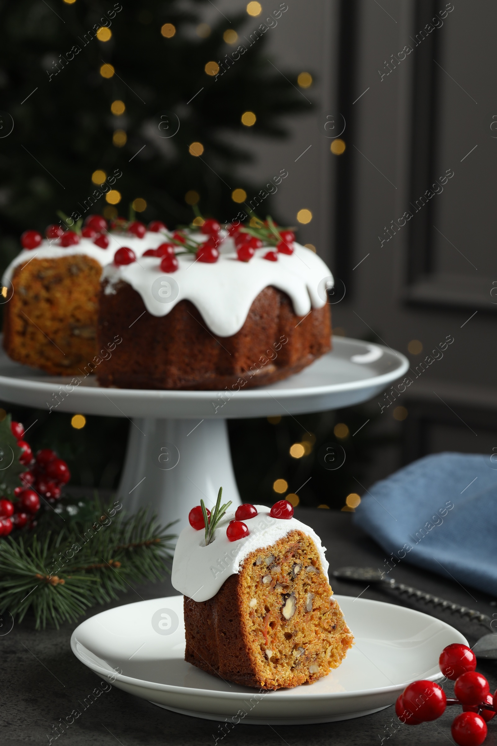 Photo of Traditional Christmas cake decorated with red currants and rosemary on table against blurred lights