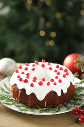 Photo of Traditional Christmas cake decorated with red currants and rosemary on wooden table