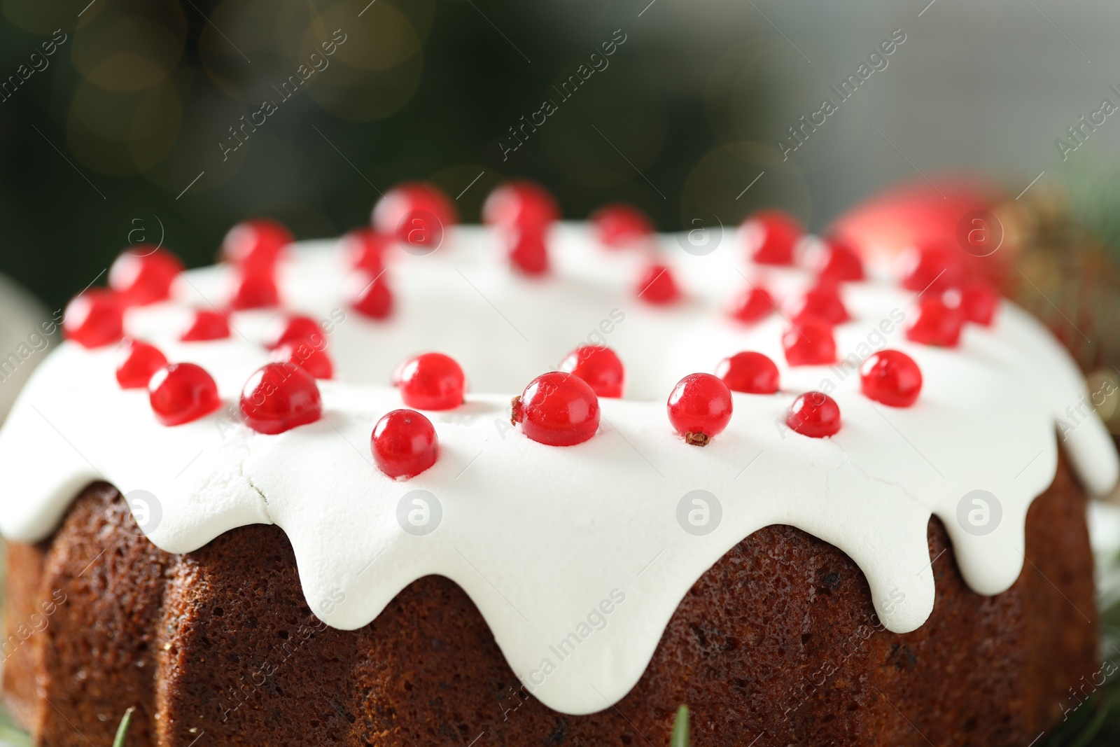 Photo of Traditional Christmas cake decorated with red currants against blurred background, closeup