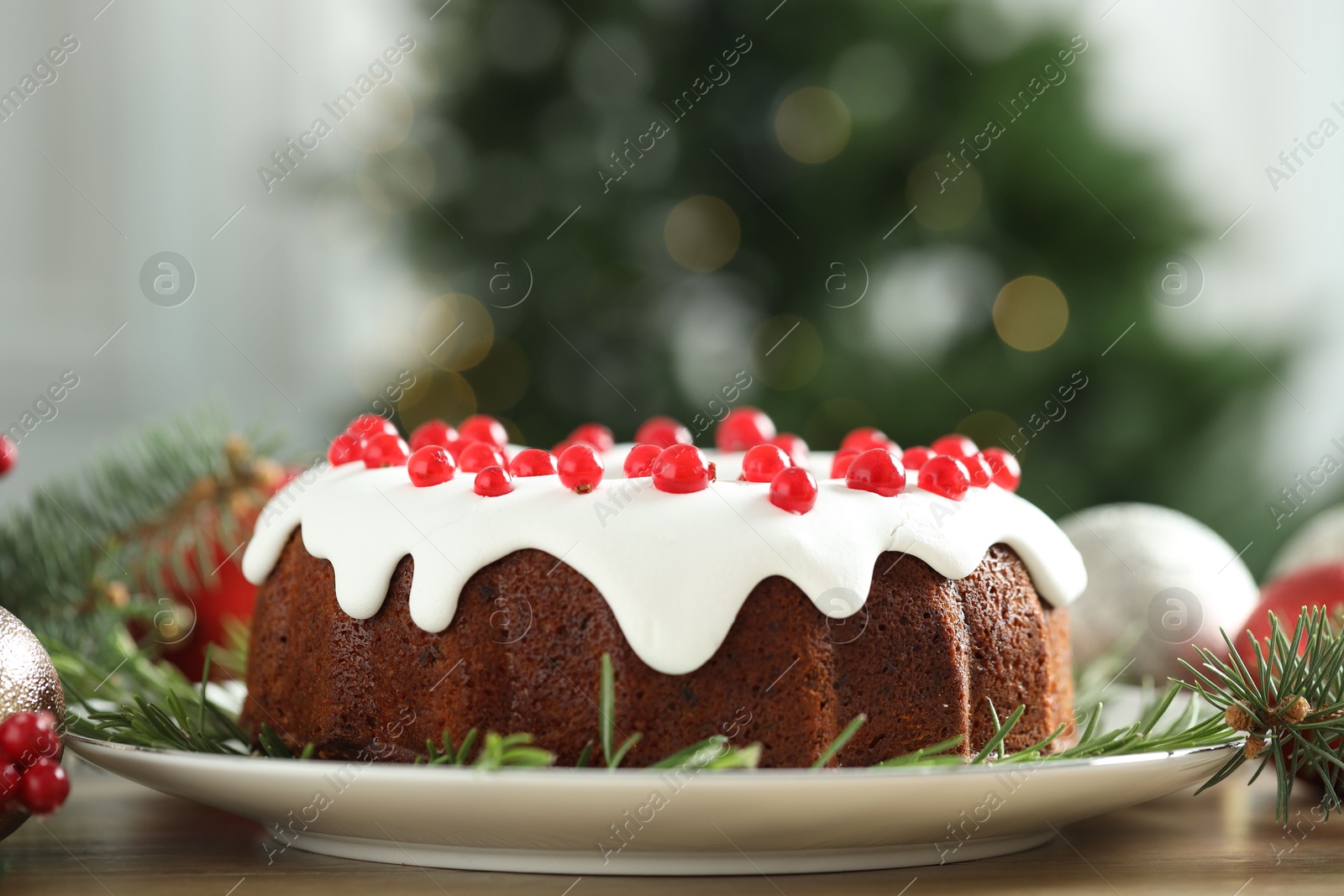 Photo of Traditional Christmas cake decorated with red currants and rosemary on wooden table, closeup