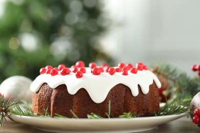 Photo of Traditional Christmas cake decorated with red currants and rosemary on wooden table, closeup