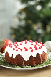 Photo of Traditional Christmas cake decorated with red currants and rosemary on wooden table