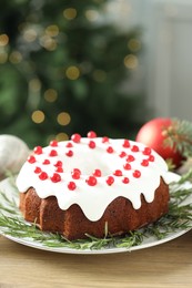 Photo of Traditional Christmas cake decorated with red currants and rosemary on wooden table