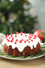 Photo of Traditional Christmas cake decorated with red currants and rosemary on wooden table