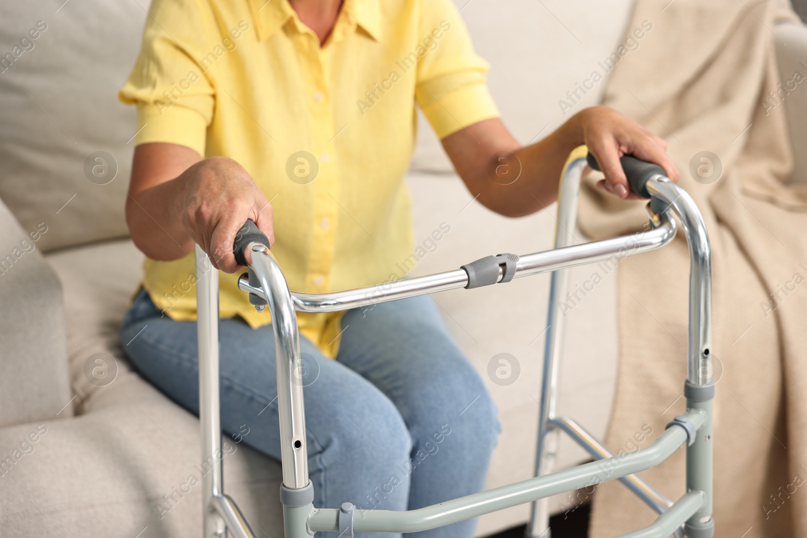 Photo of Senior woman with walking frame on sofa at home, closeup