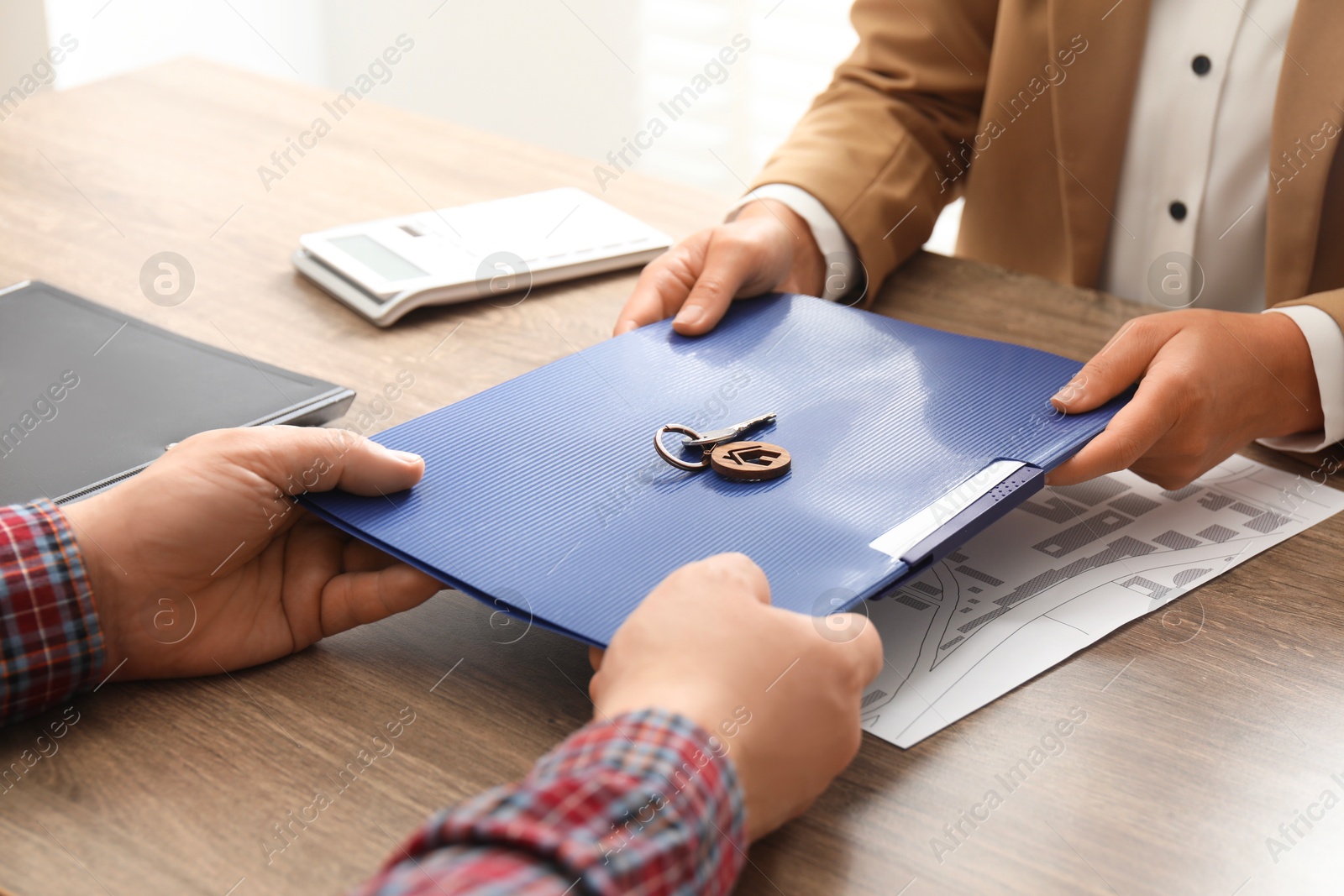 Photo of Real estate agent working with client at wooden table, closeup