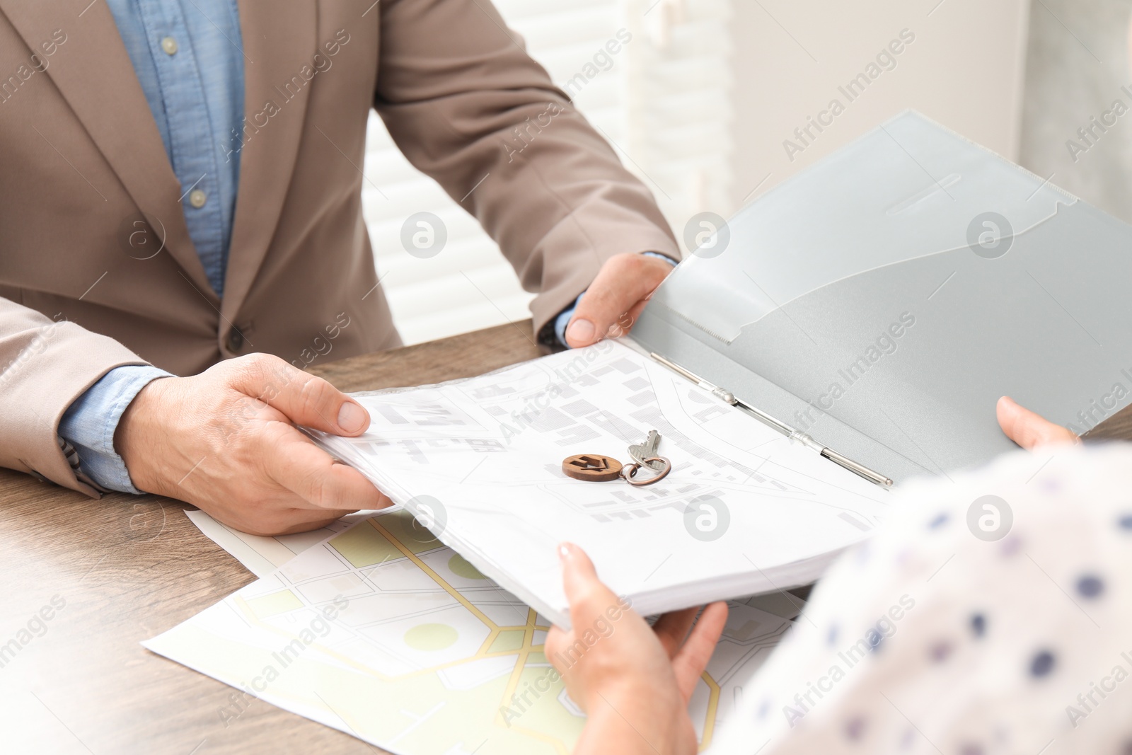 Photo of Real estate agent working with client at wooden table, closeup