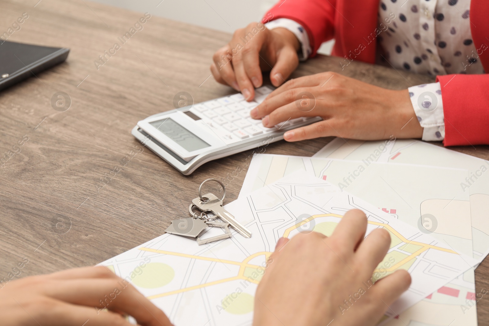 Photo of Real estate agent working with client at wooden table, closeup