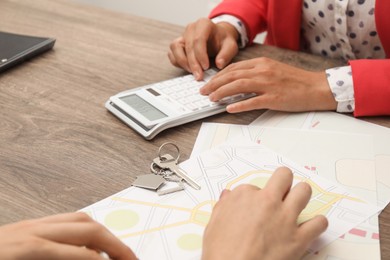 Photo of Real estate agent working with client at wooden table, closeup