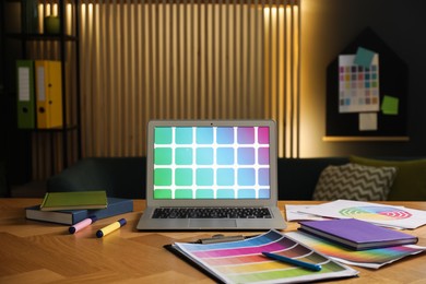 Photo of Designer's workplace with laptop, stationery and palettes on wooden table indoors