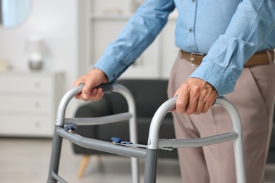 Photo of Senior man using walking frame at home, closeup