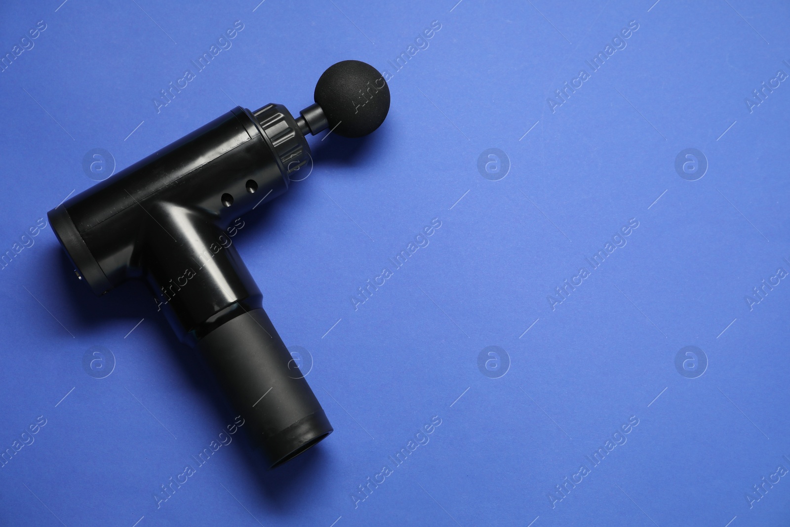 Photo of One black percussive massager on blue background, above view. Space for text